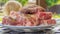 Raw meat in a plate, cut into pieces, seasoned and ready to grill, outdoors. Close-up, small depth of field