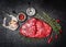 Raw meat steak and ingredients for tasty cooking on black rustic background