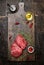 Raw meat steaks on wooden cutting board with oil, herbs and spices. Dark rustic background