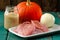 Raw meat, whole pumpkin, onion and rice with pepper mill