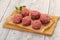 Raw meatball over wooden background