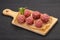 Raw meatball over wooden background