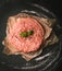 Raw minced meat, meatloaf. Raw meat, French steaks on paper, on blackboard, chalkboard, black background, vertical view.