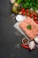 Raw minced meat on paper with fresh vegetables and spices on black background