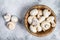 Raw mini mushroom champignon in a bamboo bowl. Gray background. Top view. Space for text