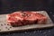 Raw New York Strip Steak on a Dark Slate Surface