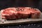 Raw New York Strip Steak on a Dark Slate Surface