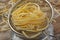 Raw noodle pasta in metal kitchen sieve