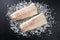 Raw Norwegian skrei cod fish filet on crashed ice on a black board