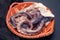Raw octopus on brown ceramic dish on black background