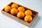 Raw Organic Cara Navel Oranges, in wooden box, on white stone  background , with copyspace  and space for text