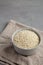 Raw Organic Carnaroli Rice in a Bowl on a gray background, side view. Space for text