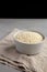 Raw Organic Carnaroli Rice in a Bowl on a gray surface, side view