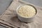 Raw Organic Carnaroli Rice in a Bowl on a gray surface, side view. Space for text