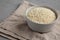 Raw Organic Carnaroli Rice in a Bowl on a gray surface, side view. Space for text