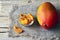 Raw organic dried mango in a glass bowl and fresh ripe mango fruit on wooden rustic table.