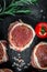 Raw Organic Fed Filet Mignon Steaks wrapped in bacon on a dark background. top view vertical image