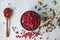 Raw organic fresh cowberry or lingonberry in a bowl and wooden spoon on white table