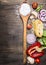 Raw pasta with mushrooms, peppers, basil and chives and vintage wooden spoon on wooden rustic background top view close up border,