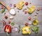 Raw pasta with peppers and cherry tomatoes with a wooden spoon, salt, butter and chives wooden rustic background top view close