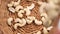 Raw peeled cashew nuts falling into a rattan wicker ecological bowl