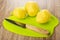 Raw peeled potatoes, knife on plastic cutting board on wooden table