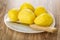 Raw peeled potatoes, knife in white dish on wooden table