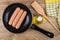 Raw peeled sausages in frying pan, vegetable oil and spatula