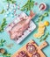 Raw pink dorado fish on ice cubes with cooking ingredients on light blue kitchen table background, top view, flat lay