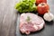 Raw pork on blackboard and vegetables on wooden background