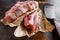 Raw pork chop warped in paper  with butcher cleaver inside over rustic metall table top view close up selective focus new wide