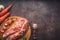 Raw pork on a chopping board on a dark wooden surface and spice for cooking. Food background with copy space. Toned