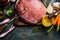 Raw pork ham meat preparation with cooking ingredients: vegetables and favoring , and meat fork on dark rustic background