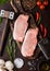 Raw pork loin chops on old chopping board with salt and pepper and vintage meat hatchets and hammer on rusty background.Red pepper