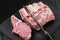 Raw pork loin, knife and fork on slate plate