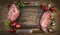 Raw pork meat chops with kitchen tools, fresh seasoning and ingredients for cooking on rustic wooden background, top view, frame.