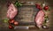 Raw pork meat chops with kitchen tools, fresh seasoning and ingredients for cooking rustic wooden background, top view, frame.