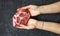 Raw pork meat. Woman hands holding one slice of steak