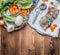 Raw Pork roast on white backing paper with vegetables and condiment, preparation on rustic wooden background, top view