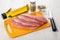 Raw pork schnitzel on cutting board, oil, pepper, condiment, kni