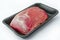 Raw pork steak in black packaging on white. Raw beef steak in black packaging on a white background. Fresh Raw Meat in package,