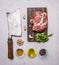 Raw pork steak on a cutting board and vintage meat cleaver with spices, garlic and herbs on wooden rustic background top view clos