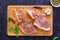 Raw pork steak with herbs on dark background. Raw juicy steak on bone. Top view