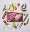 Raw Pork steak with vegetables and herbs, meat knife and fork, on a cutting board wooden rustic background top view close up