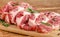 Raw pork steaks on cutting board with pepper and rosemary on wooden background.