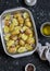 Raw potatoes with olive oil and spices in the baking dish. The preparation of baked potatoes.