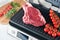 Raw prime steaks on electric grill. Black angus prime meat steaks Ribeye on modern electric grill with rosemary, cherry tomato