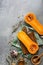 Raw pumpkin halves or butternut squash, cutting board, herbs, honey on a gray background. Top view, flat lay, copy space