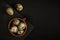Raw quail eggs in a brown clay cup and on a black stone plate on a textured dark concrete surface. moody artistic mockup with copy