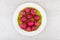 Raw radishes in green glass plate on wooden table